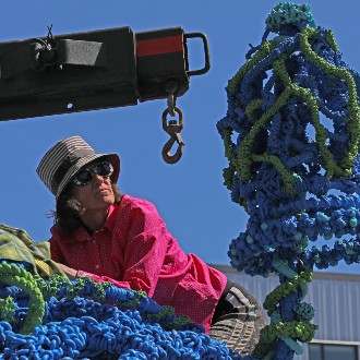Pamela Moulton climbs atop her sculpture TANGLE to check for damage during its move to the Portland Campus.