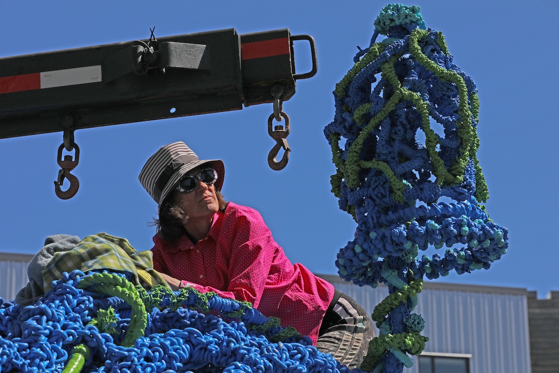 Pamela Moulton climbs atop her sculpture TANGLE to check for damage during its move to the Portland Campus.