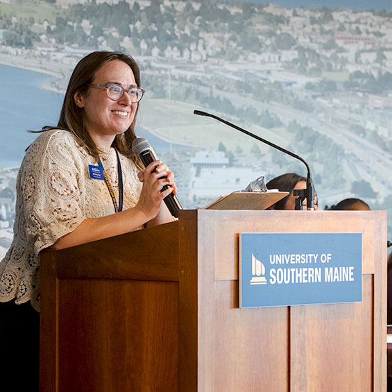 Jill Piekut Roy speaks at a podium in the Glickman Family Library Events Room.