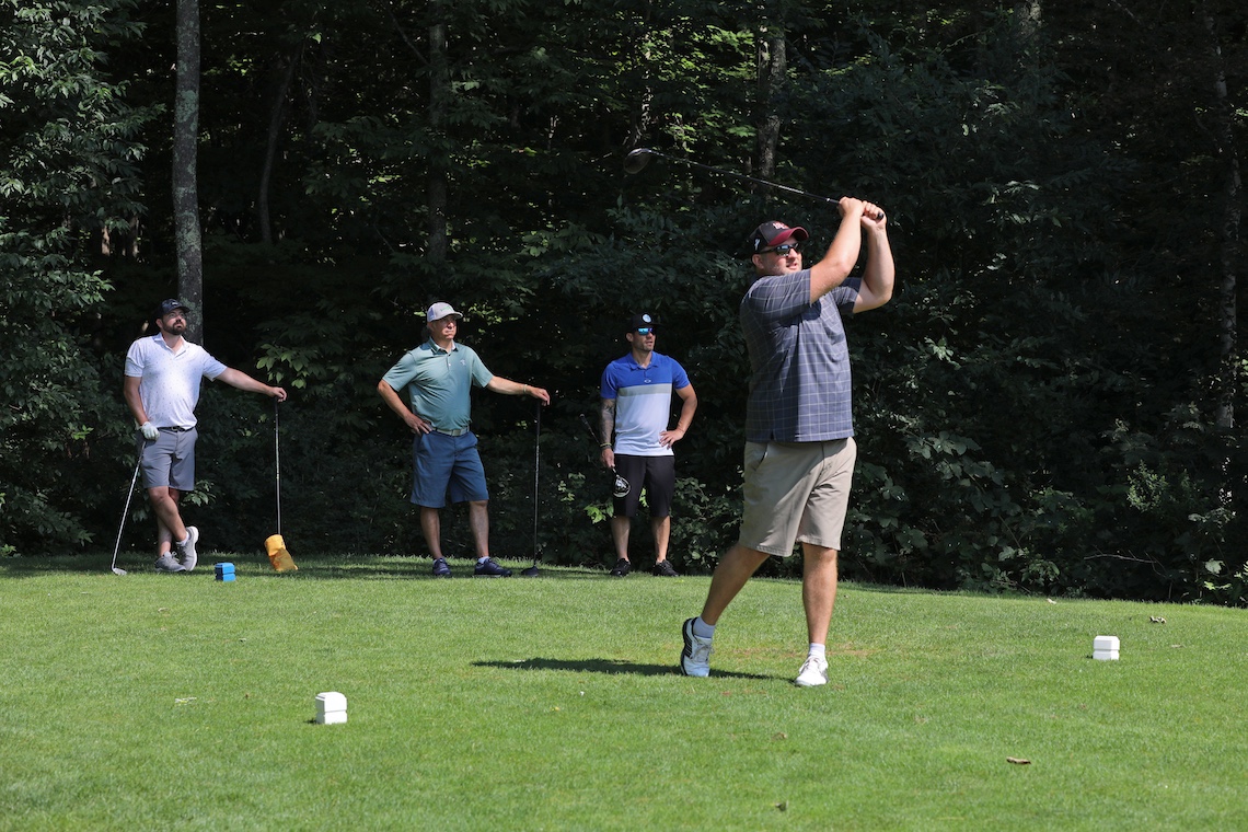 A golfer holds his follow-through as he watches the arch of his drive at the 2024 Husky Golf Classic.