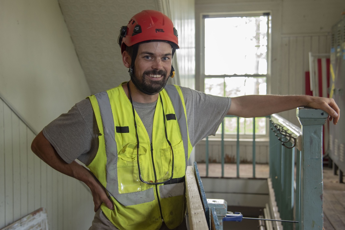 Lee Hoagland stands at the stairway where he found a large bundle of notes while renovating a wall at the Academy Building.