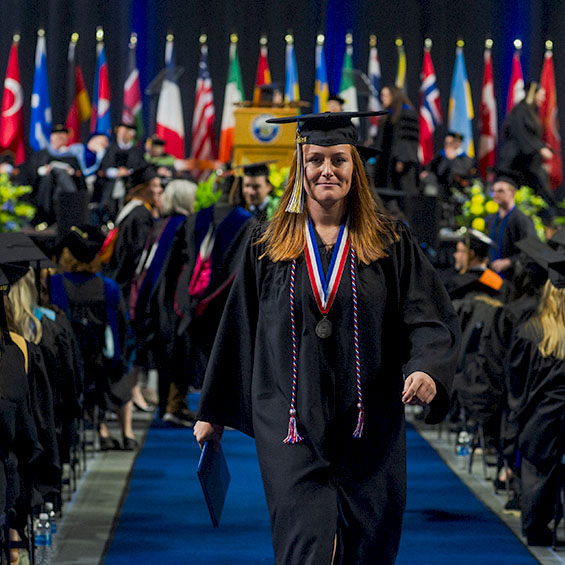 A graduate walks confidently down the aisle after receiving their diploma.