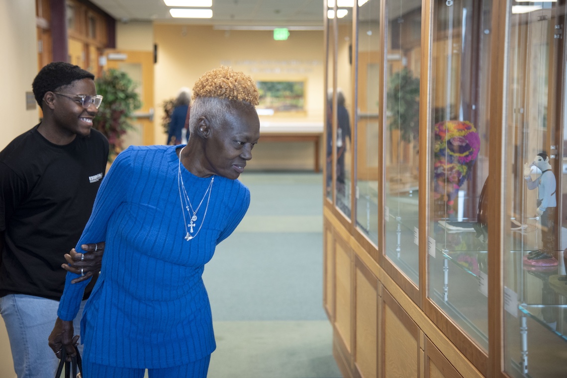 Visitors to the Employee Art Exhibition admire the items in the display case on the seventh floor of Glickman Library.