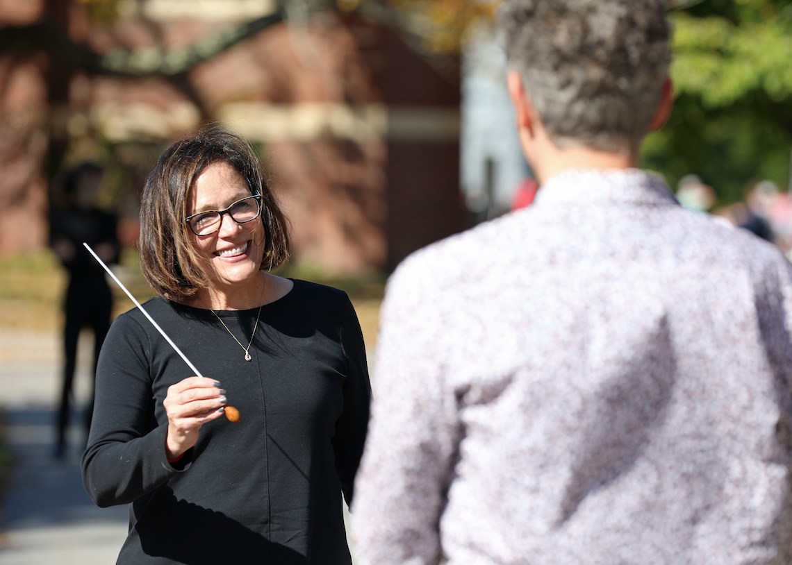 President Jacqueline Edmondson returns the baton to Dr. Will Kinne after conducting one of the musical pieces in the Osher Wind Ensemble's annual homecoming concert.