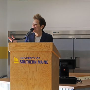 Coach Angel Elderkin ’99 speaking at a podium during National Girls & Women in Sports Day event at USM