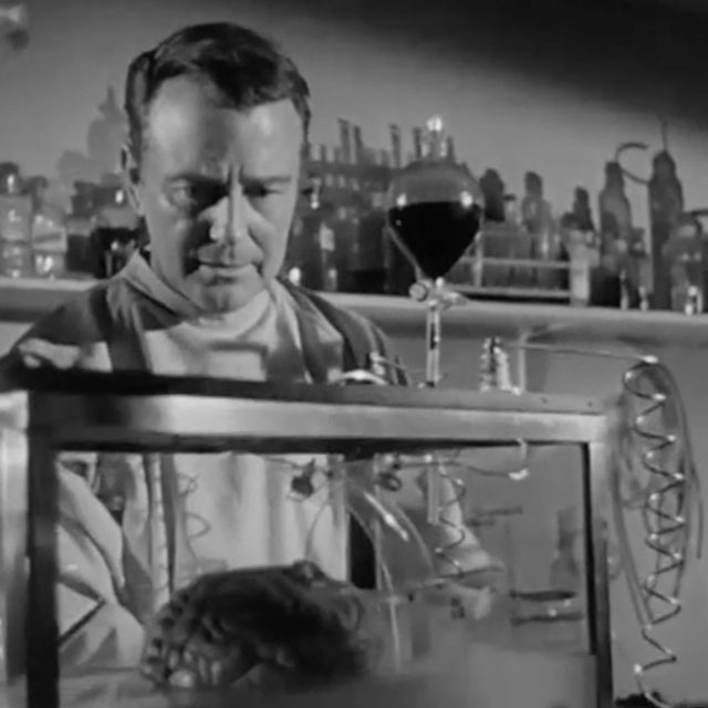 Lew Ayres, actor playing Dr. Cory, inspects Donovans-brain-in-Donovans-Brain-USA-1953 black and white film