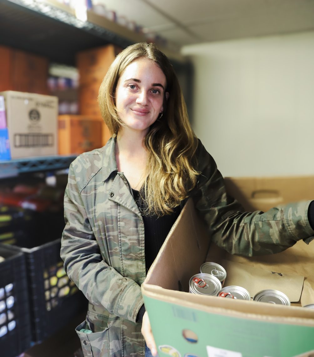 Sarah Farrugia holding a box with canned goods.
