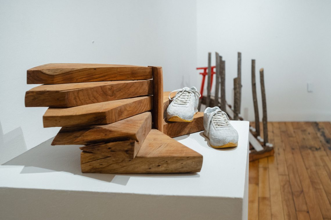 Artist Lin Lisberger exhibition featuring sculpture of a pair of shoes on a staircase, made from assorted hardwood.