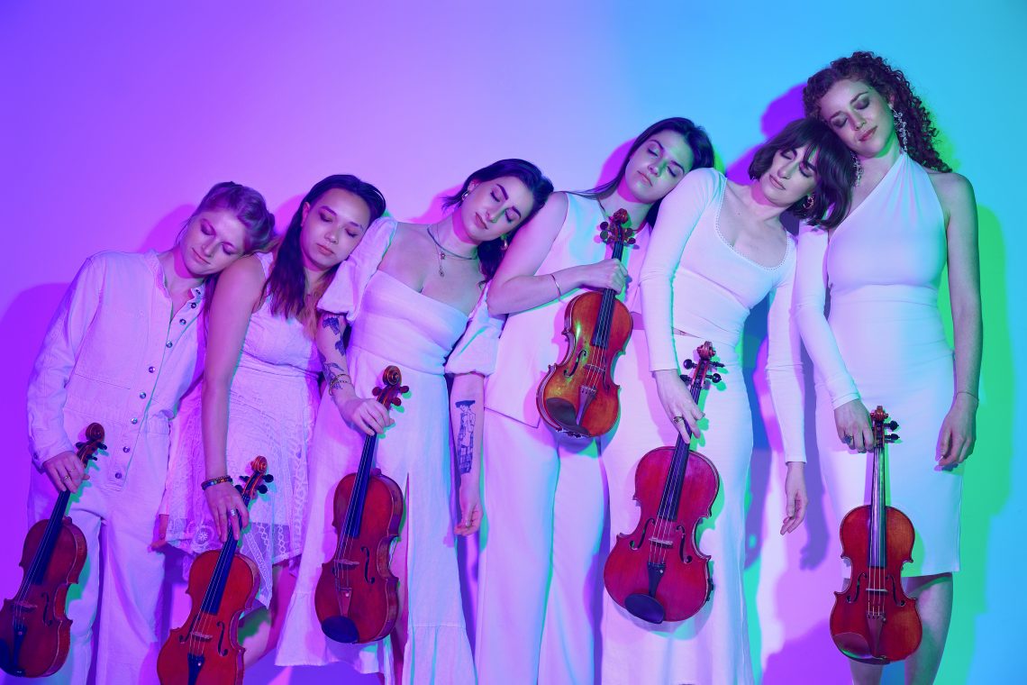Members of Palaver strings lean on one another, each holding a violin or viola.