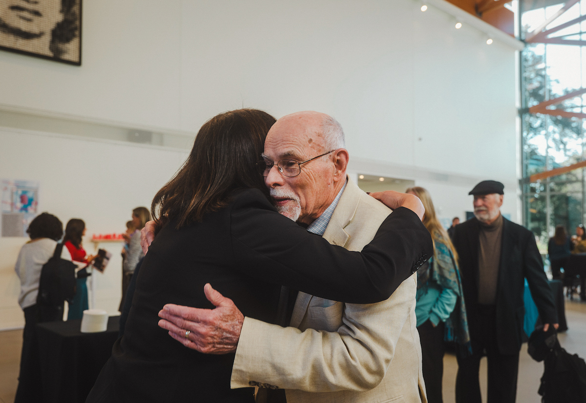 President Edmondson and Dr. Smith Embrace in gallery hall of Crewe Center