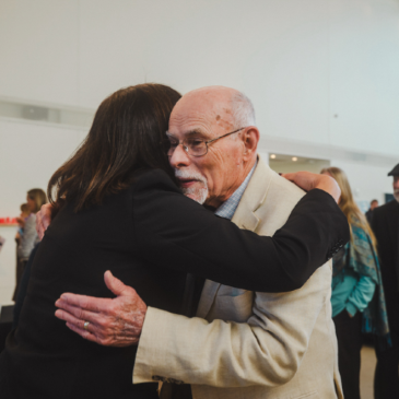 President Edmondson and Dr. Smith Embrace in gallery hall of Crewe Center