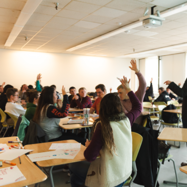 Students raise their hands in a USM business school classroom