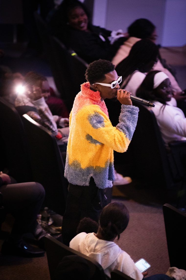 Afrochella performer sings into microphone as he walks towards the stage through the audience