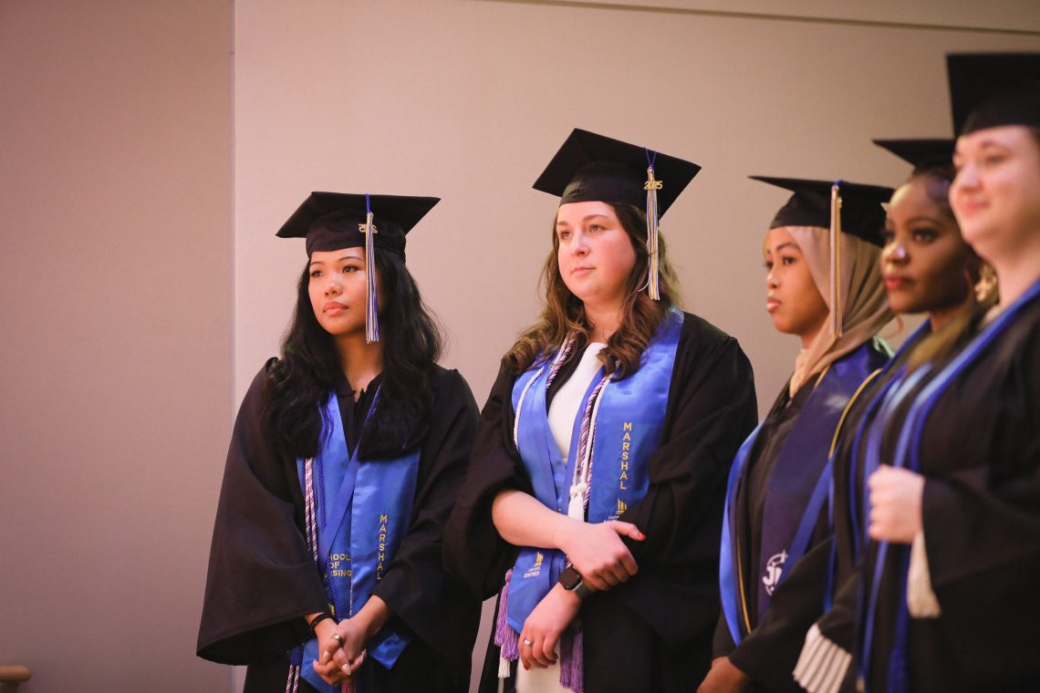 University of Southern Maine nursing class marshals Elle Marshall and Phoebe Sykes listen during a commencement address