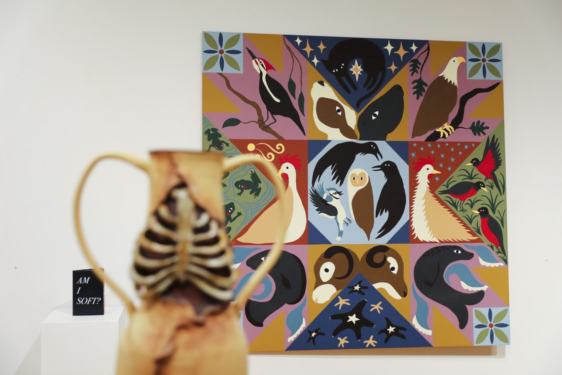 A ceramic vase in the foreground with a painting in the background at the USM Gorham Art Gallery during the 2026 Juried Student Art Exhibition.