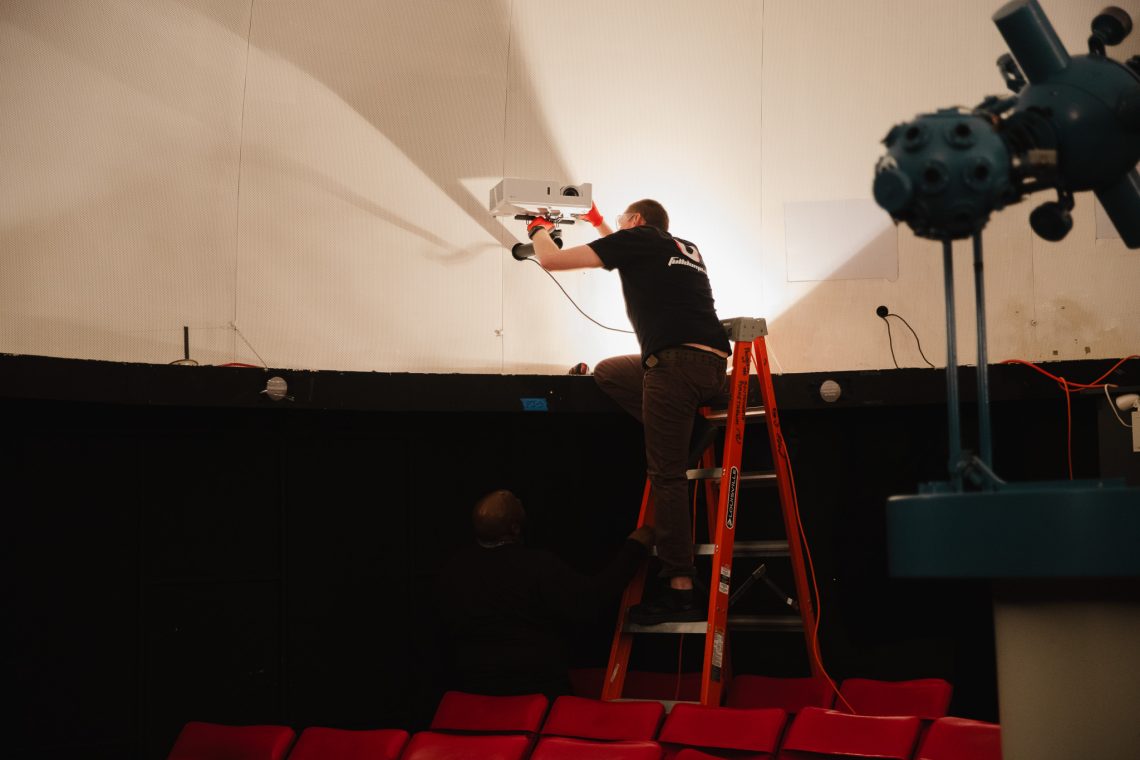 Technicians install new digital projectors inside the Southworth Planetarium as part of its 2026 upgrades.
