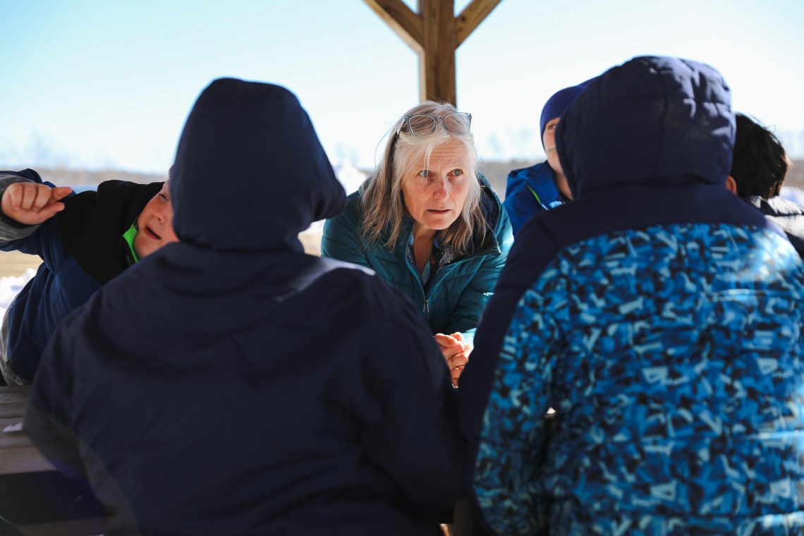 Becky Hallowell chats with students as they work together during an outdoor learning activity at Wiscasset Elementary School.