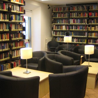 Black arm chairs and table lamps between bookstacks in a library