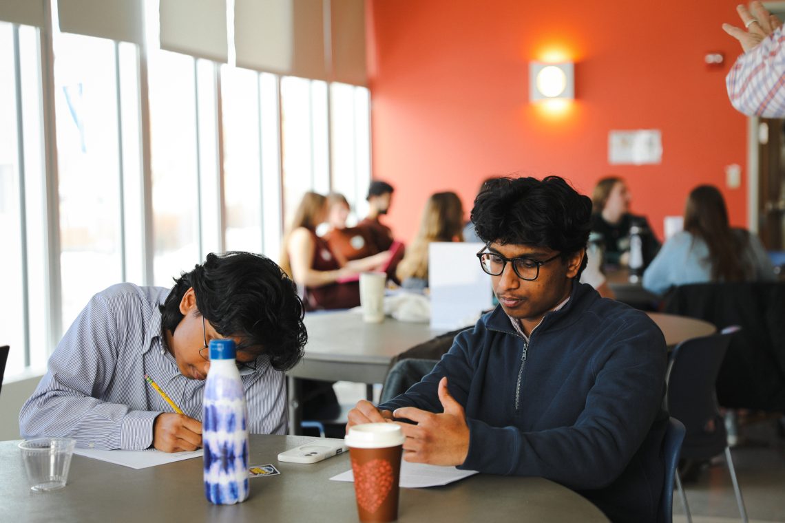 Two brothers on same team prepare materials before presenting their pitch at innovation challenge