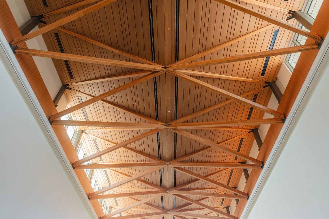 View of the Great Hall Gallery’s mass timber ceiling at the Crewe Center for the Arts, featuring exposed wooden beams and natural light.