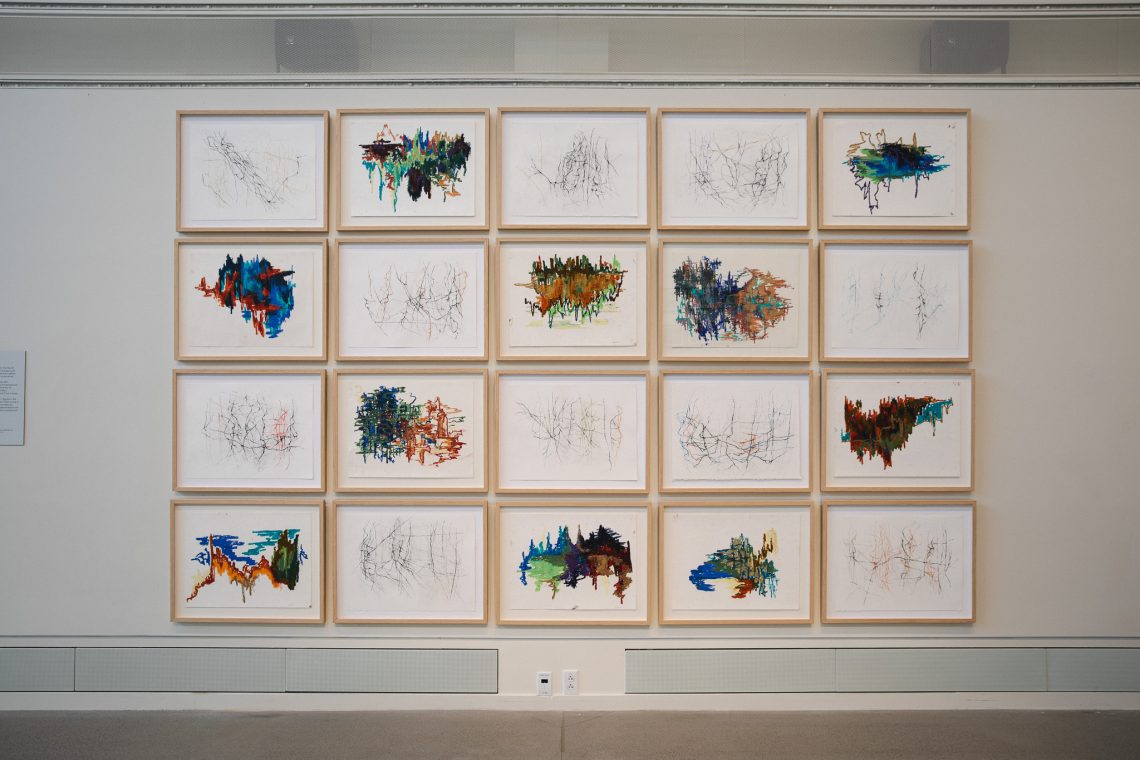 A wall of framed drawings and paintings displayed as part of Peter Bruun's 'Communion' series, on view in the 'Even As We Grieve' exhibition at the Crewe Center for the Arts.