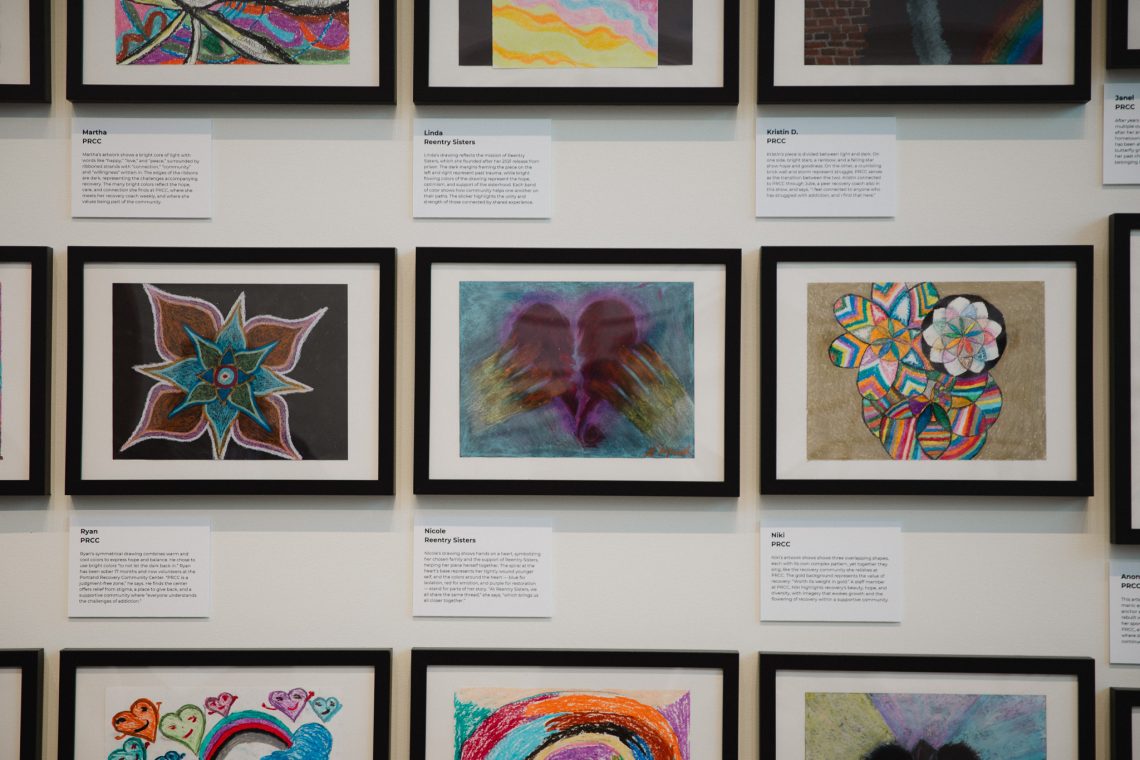 Rows of framed artwork created by community members during nonprofit art workshops, on view as part of USM's 'Even As We Grieve' exhibition at the Crewe Center for the Arts.