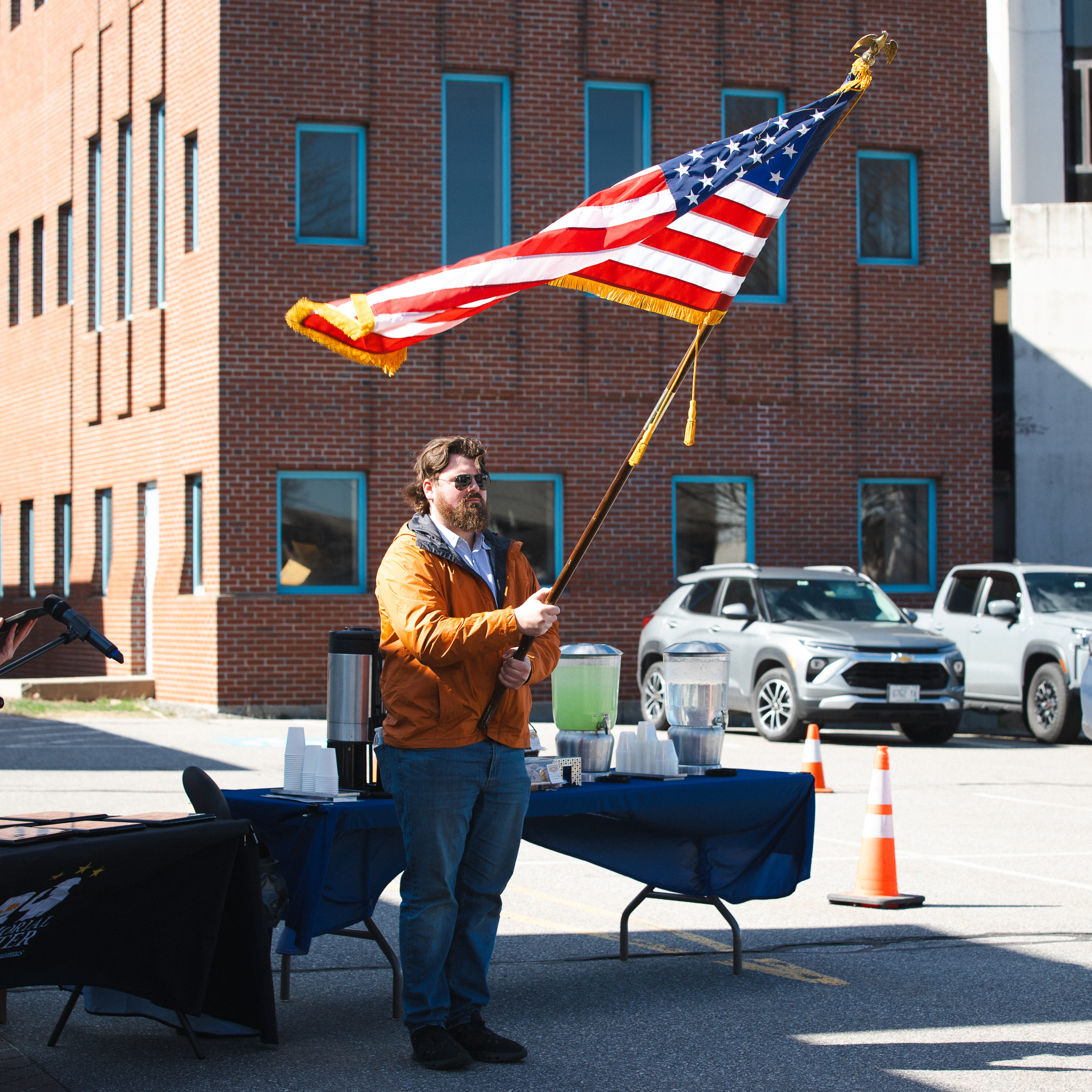 A man holds an American flag aloft during the national anthem at USM's Veterans Row Dedication Ceremony on April 23, 2026.