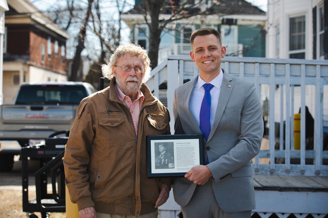 Paul Donahue and Nathanial Twombley smile while holding a plaque honoring 1st Lieutenant Louis A. Donahue at USM's Veterans Row Dedication Ceremony on April 23, 2026.