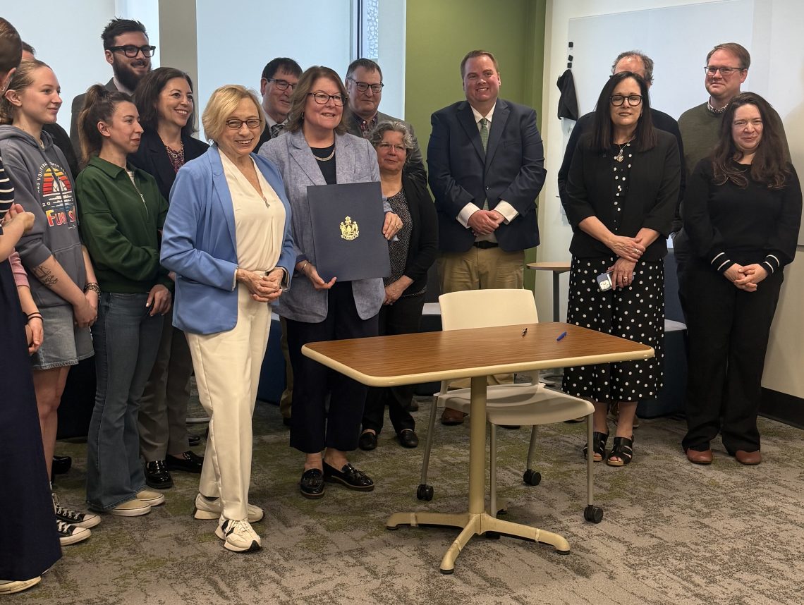 Governor Janet Mills ceremoniously singing bill at CTI for increased educator wages.