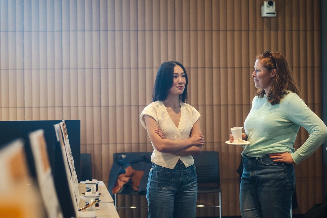 Career Exploration Internship Program Poster Exhibition indoors. Two students chat about posters.
