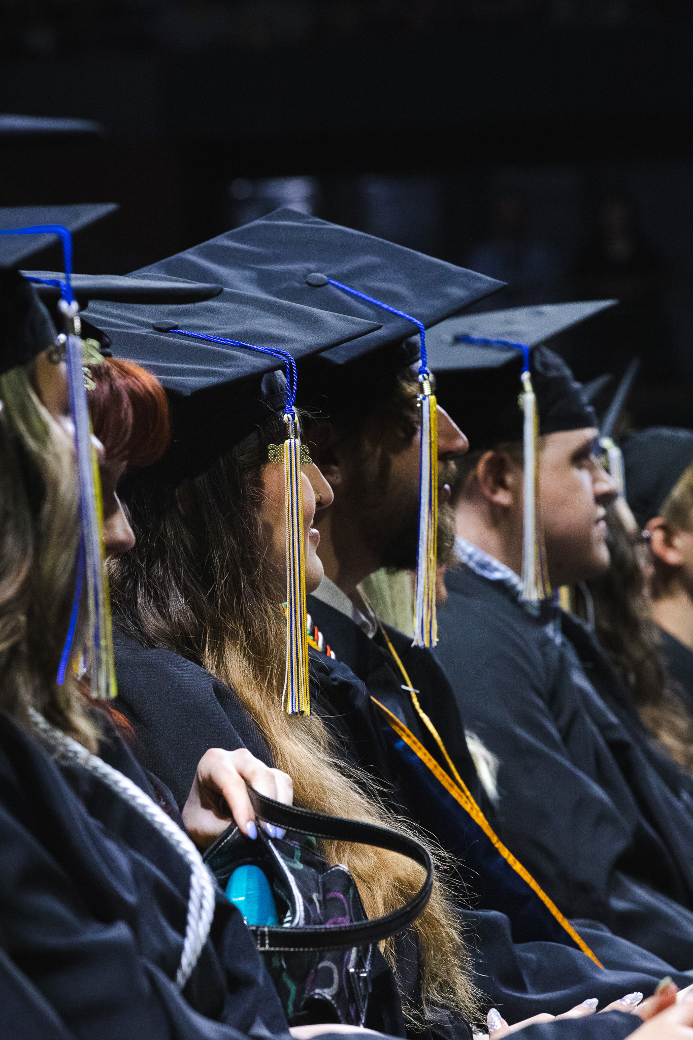 Students in full commencement regalia looking at the stage.