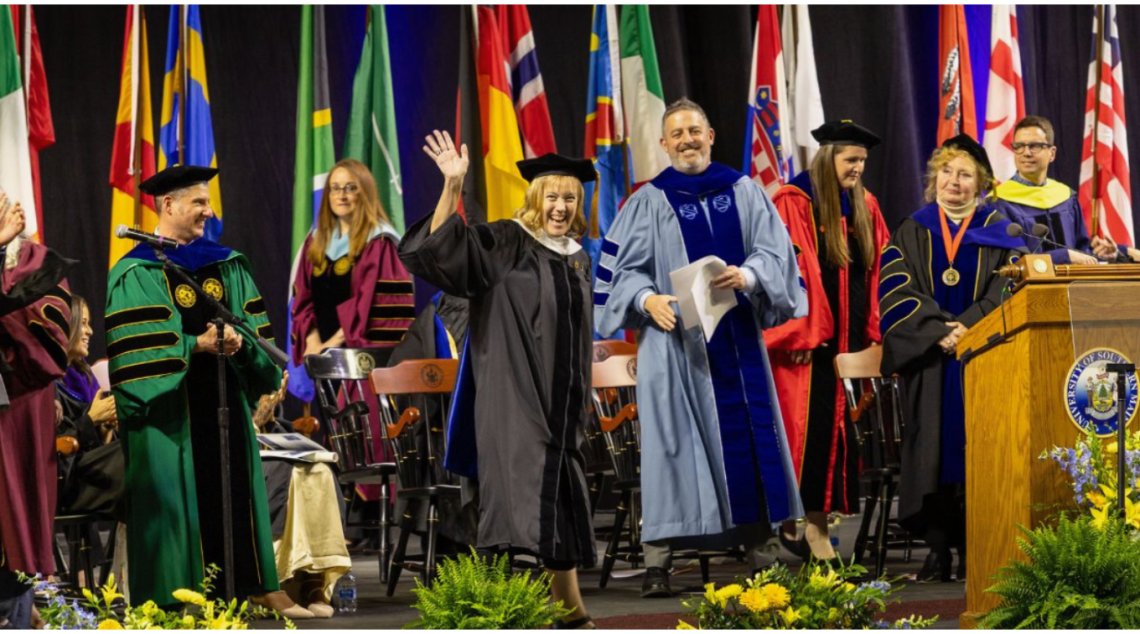 Graduating student waiving and receiving diploma