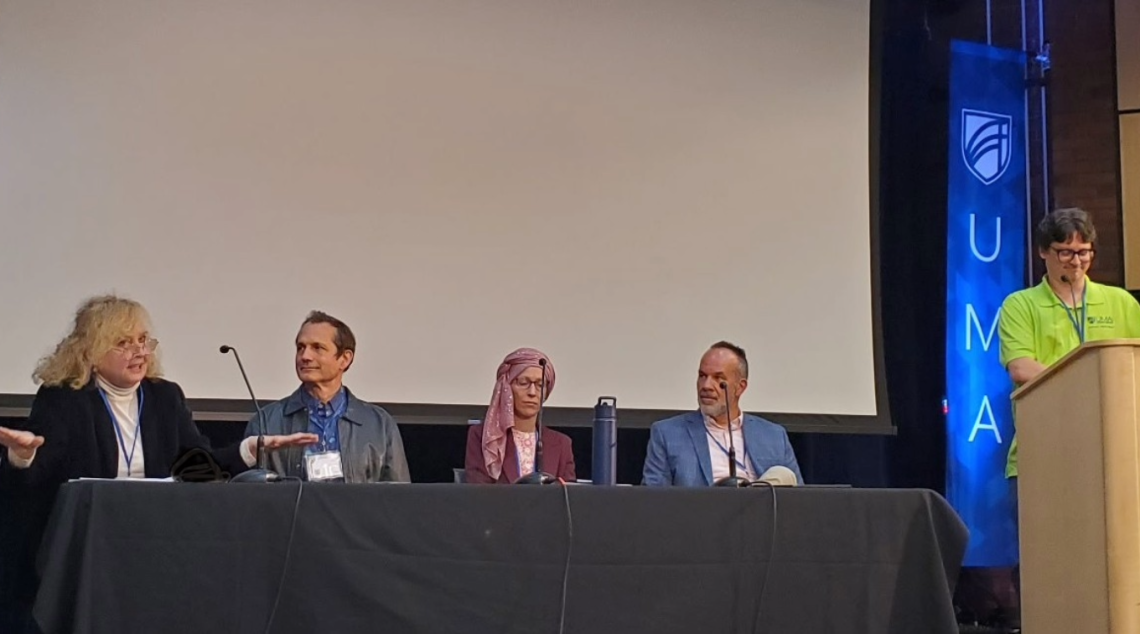 5 panelists behind a table and podium