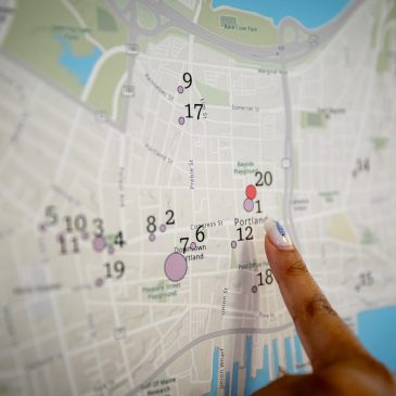 Attendee of mapping event pointing at a mark of interest on a map of Portland, Maine.