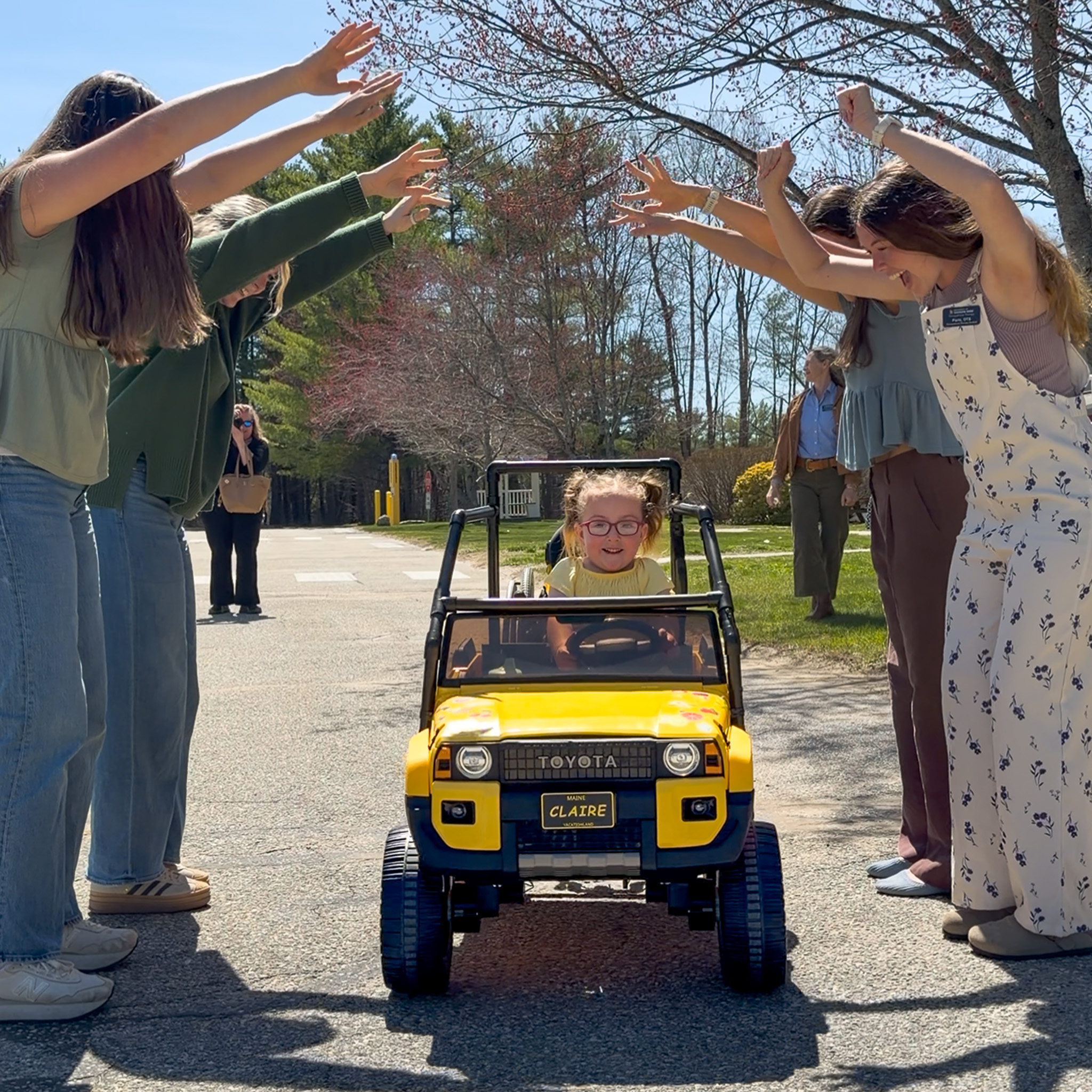 USM Students celebrate the delivery of a modified mobility toy car by creating a tunnel for young recipient, Claire, to drive through.