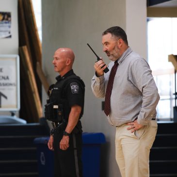 An officer and an administrator coordinate over radio during USM's school reunification exercise.