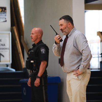 An officer and an administrator coordinate over radio during USM's school reunification exercise.