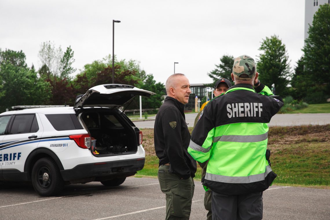 Sheriff's deputies and an Andover police officer confer near a sheriff's vehicle during a Search and Rescue training session at the Response Ready: Public Safety UAS Conference.