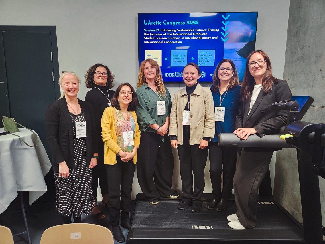 Presenters and participants gather in front of a screen displaying Session 87 at the UArctic Congress 2026, titled "Catalyzing Sustainable Futures: Tracing the Journeys of the International Graduate Student Research Cohort in Interdisciplinarity and International Cooperation."