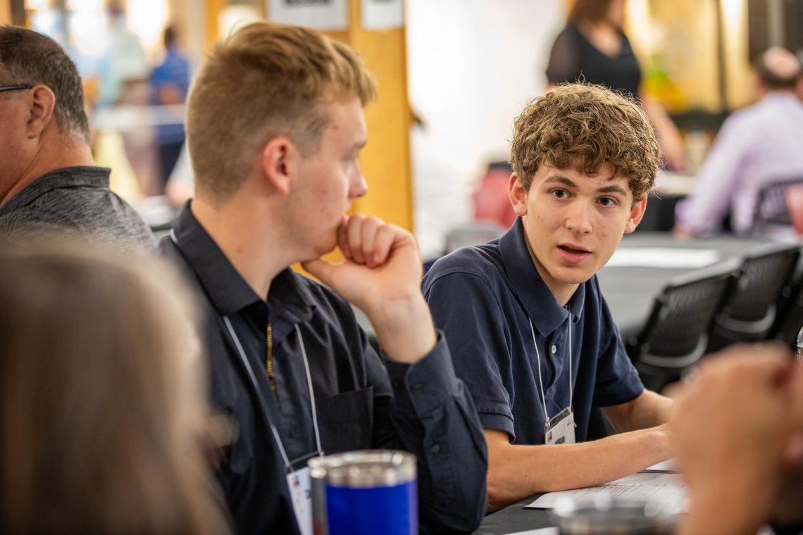 Two student delegates confer at a table during a discussion session.