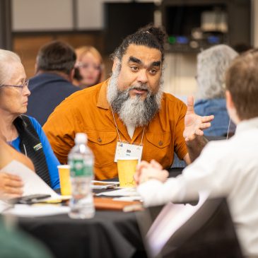 A delegate gestures while making a point during a table discussion.