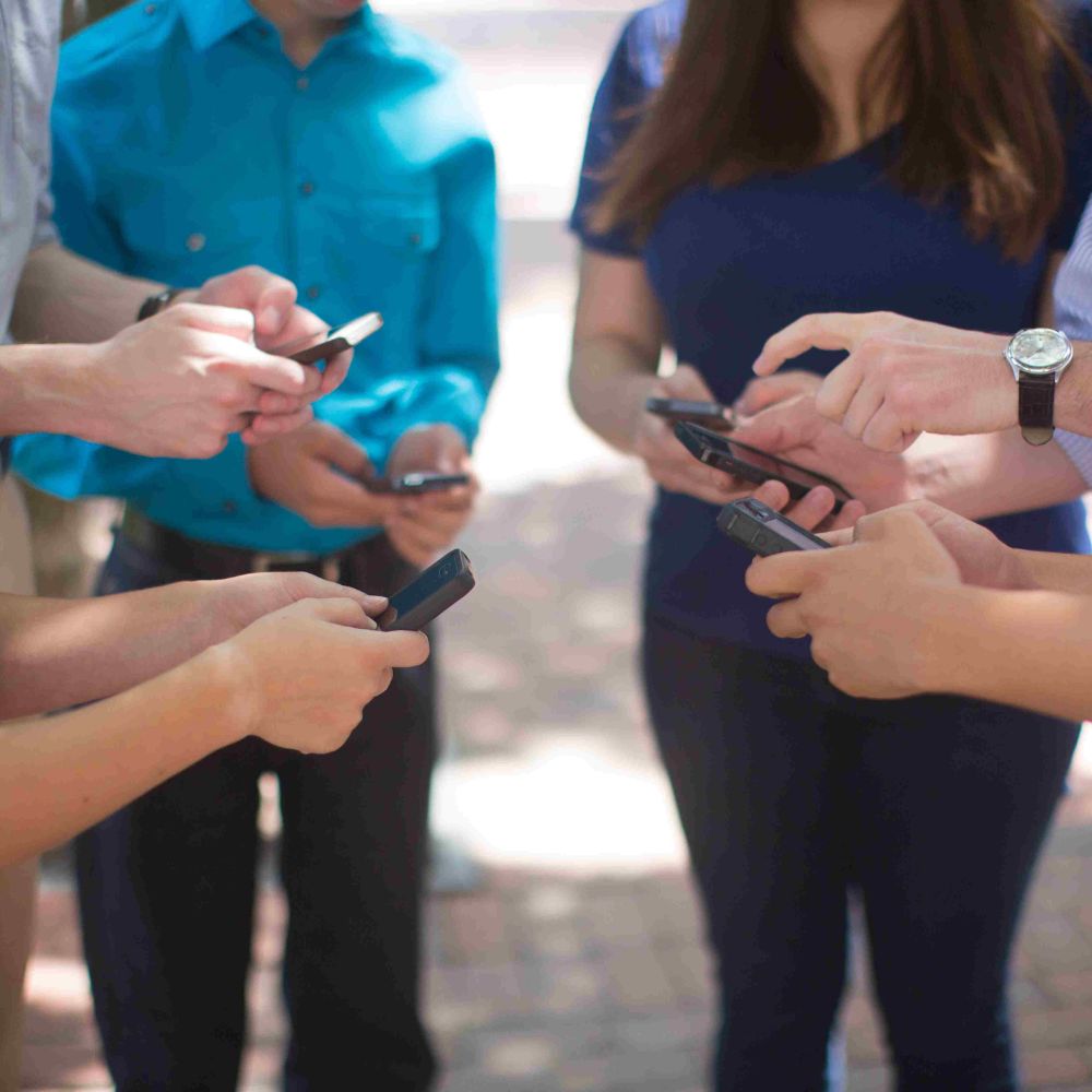 Students on their cellphone standing in a circle.