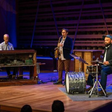 Mike McGinnis and pianist and drum kit player performing.