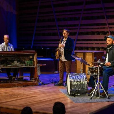 Mike McGinnis and pianist and drum kit player performing.