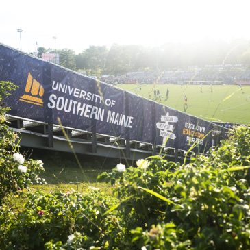 A University of Southern Maine banner marking USM as Exclusive Education Partner lines the stands at Fitzpatrick Stadium during a match.