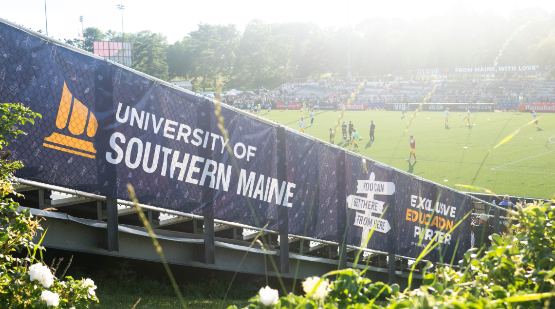 A University of Southern Maine banner marking USM as Exclusive Education Partner lines the stands at Fitzpatrick Stadium during a match.