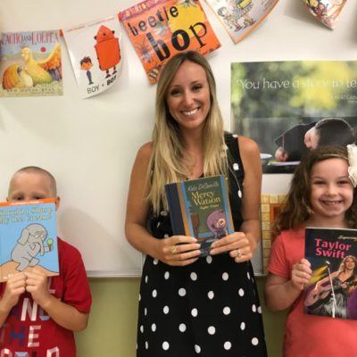 Students with their teacher each holding a book