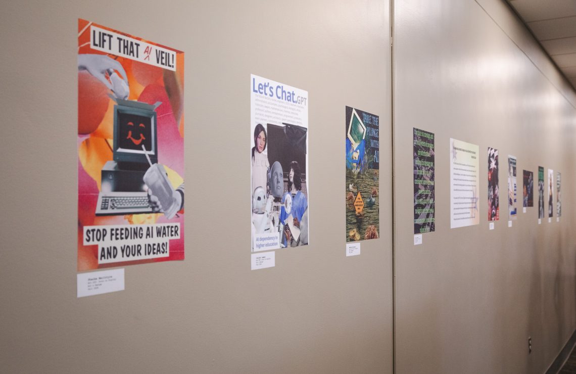 A row of colorful photo collage posters by ART 222 students hangs along a hallway wall in the Gorham Campus Library