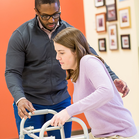 An graduate OT student practices assistance for use of a walker.