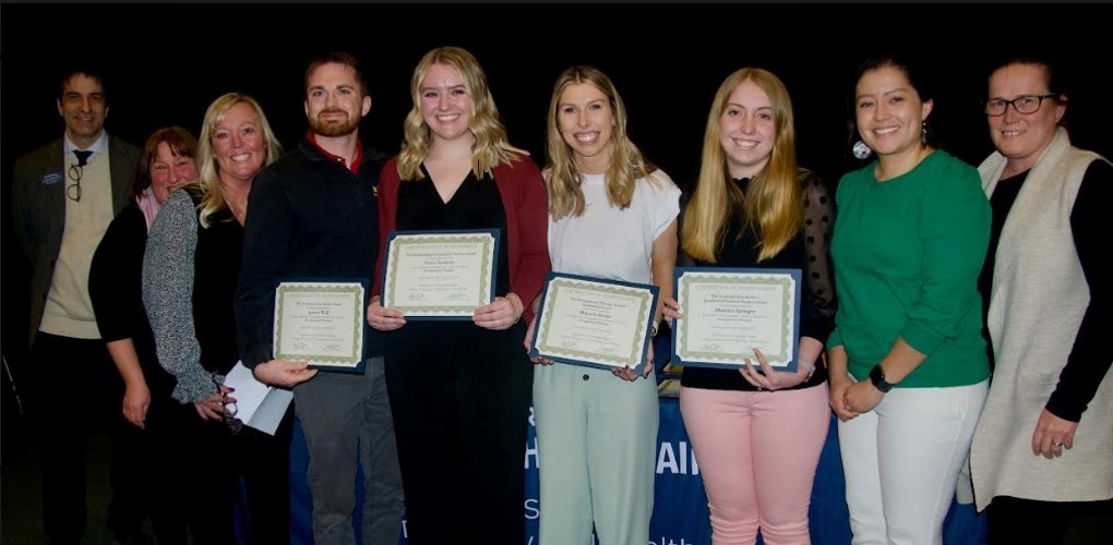 Four students holding awards next to five faculty and staff from USM.